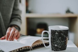 Bible and coffee on desk representing morning devotion before work.: Early morning light shining through a church window, with hands clasped in prayer: Open Bible and coffee cup for morning prayer reflection.